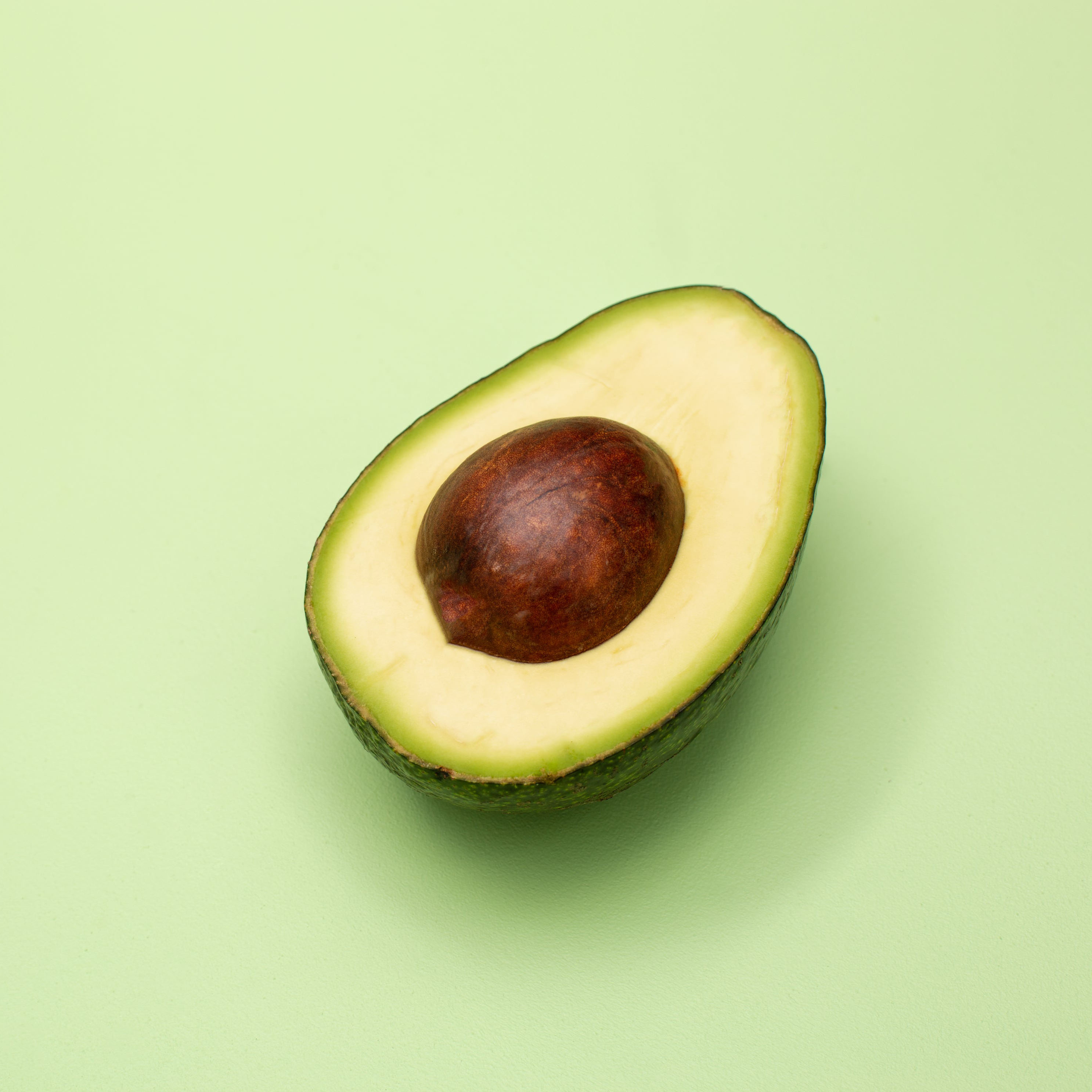 half of an avocado with green background